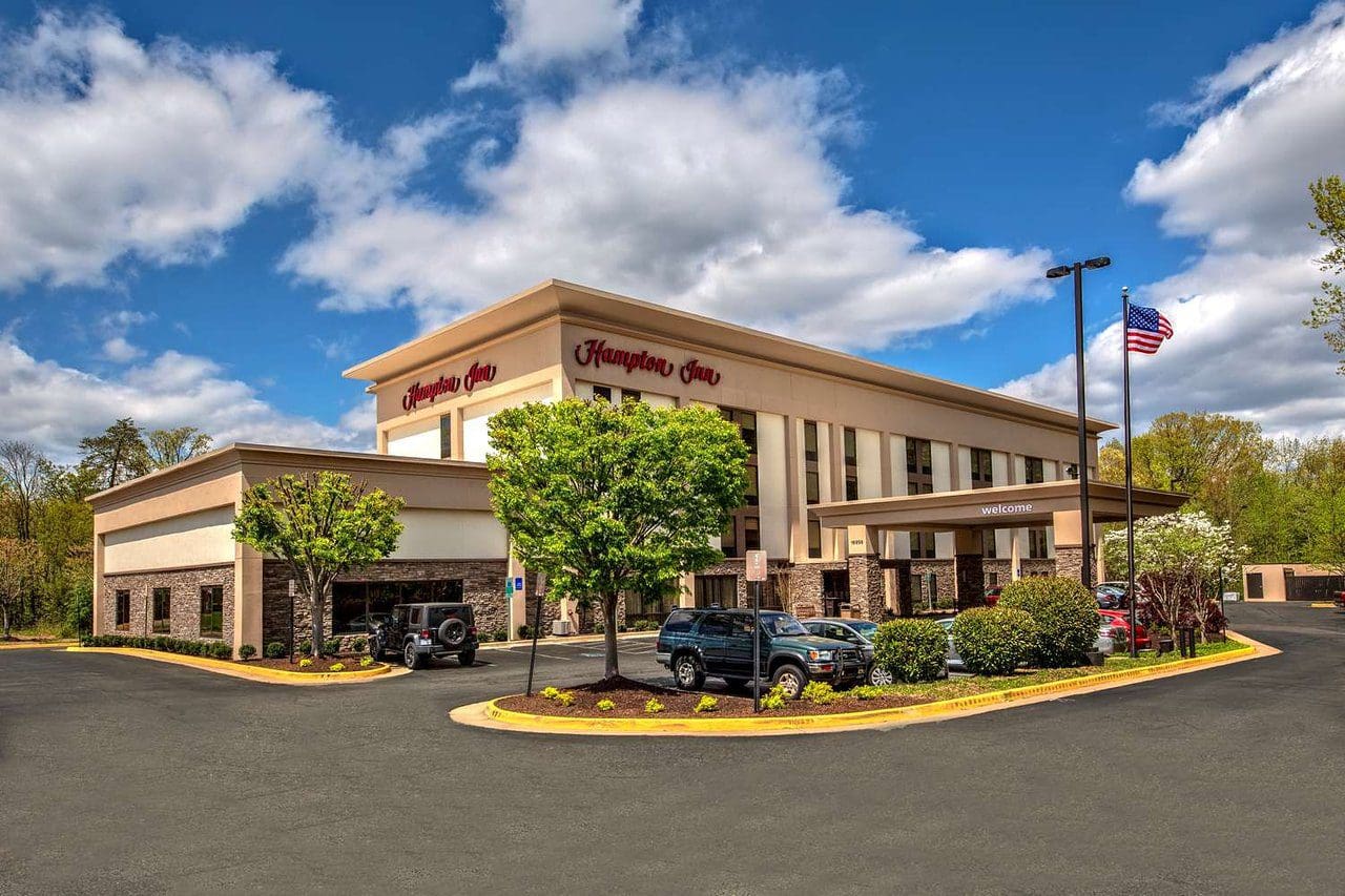 Modern commercial building with parked cars under a blue sky.